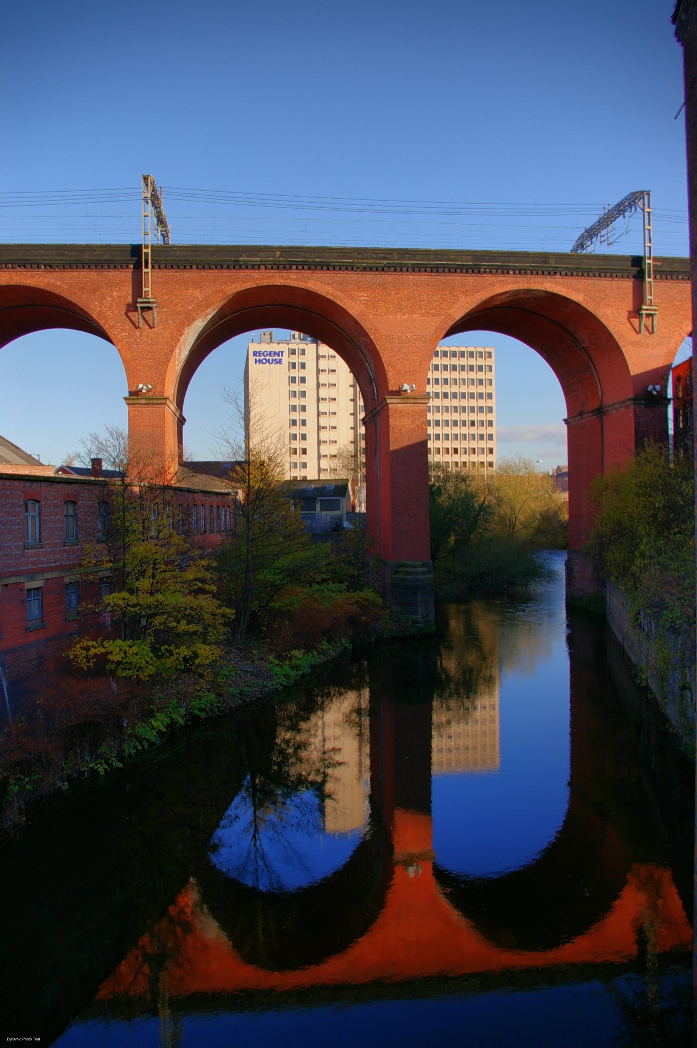 Stockport Viaduct in low sun, its arches reflected in the River Mersey